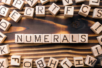 word numerals composed of wooden cubes with letters,  symbol that represents a number concept scattered around the cubes random letters, top view on wooden background