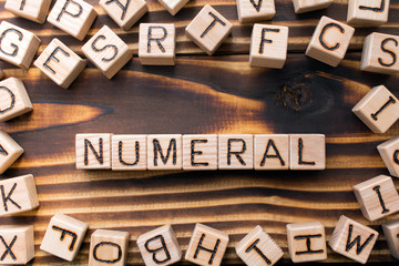 word numeral composed of wooden cubes with letters,  symbol that represents a number concept scattered around the cubes random letters, top view on wooden background