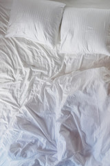 Messy bed with white pillows and sheets