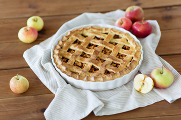 food, culinary and baking concept - apple pie and kitchen towel on wooden table