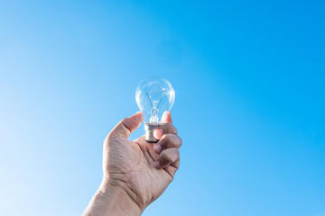 hand holding light bulb and blue sky background