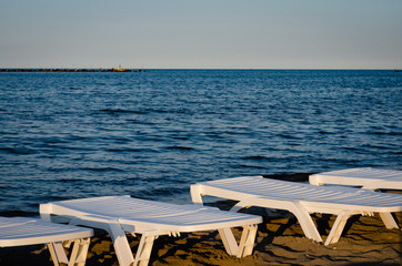 Empty white plastic sunbeds set on the seafront, during summer  season.