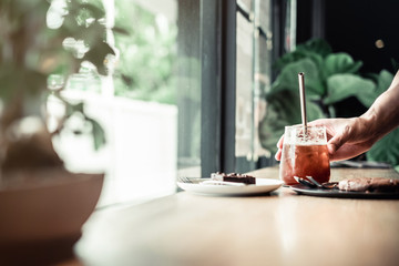 Man hand take coffee and cake on wooden table coffee shop background
