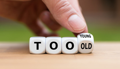 Hand turns a dice and changes the expression "too old" to "too young" , or vice versa.