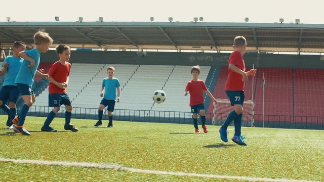 Little boys training soccer on big stadium, dribbling and making goal