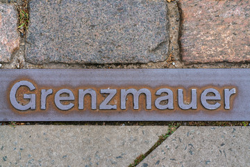 Metal plate on a walkway in Berlin indicating where the Berlin wall stood