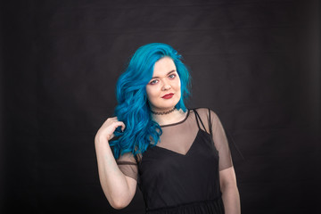 People and fashion concept - Young and attractive woman with black lipstick and blue hair posing over black background