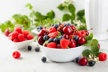 Berries closeup colorful assorted mix of strawberry, blueberry, raspberry and sweet cherry on a white table.