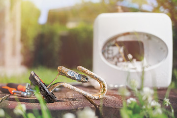 Heating element, rust and scale on boiler background, lying on wooden table. Light. Concept of repair and maintenance of home appliances