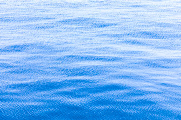 The background or texture of the blue water surface of the river, lake or sea with the waves, ripples and flares