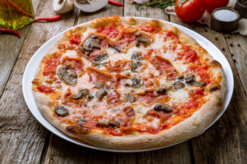Pizza with ham and mushrooms on wooden table