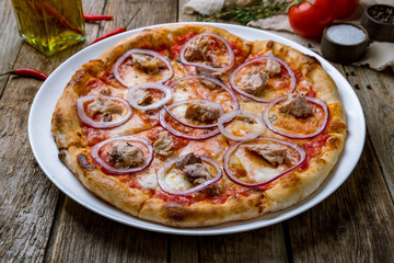 Pizza with tuna and red onion on wooden background