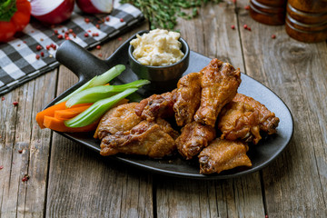 Fototapeta premium Buffalo chicken wings on black plate on wooden background