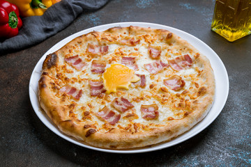 Carbonara pizza with bacon on dark concrete background