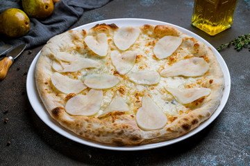 Pizza with pears and Gorgonzola cheese on dark concrete background