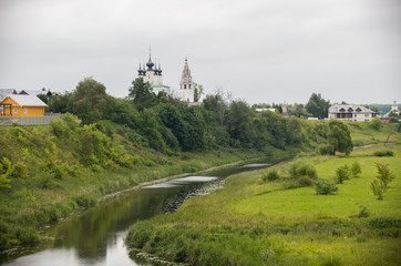 A landscape of small village - a small stream - church on a background
