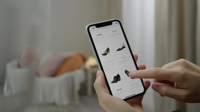 Woman is Online shooping by smart phone. Choosing woman shoes. Shot on RED film camera