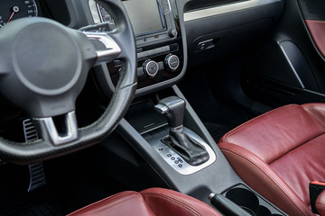 Luxury car interior with dashboard, steering wheel and leather seats, close up