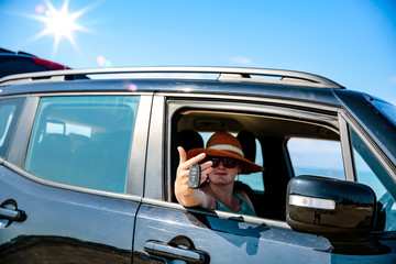 Black summer car and a girl on the beach. Happy smiling woman on the seashore view.