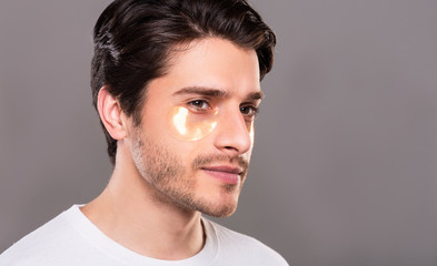 Young man with golden patches under eyes from wrinkles