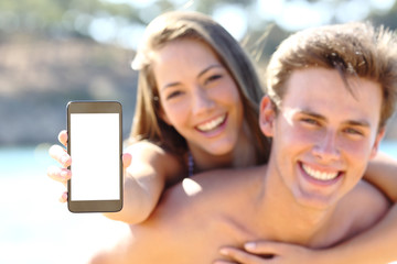 Happy couple on the beach showing blank phone screen