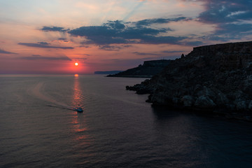 A boat sailing in the sunset