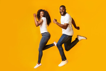 Fototapeta na wymiar Joyful afro man and woman are running in the air