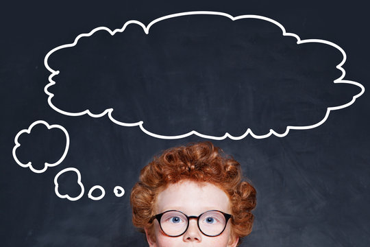 Child boy and big empty speech clouds bubbles on blackboard
