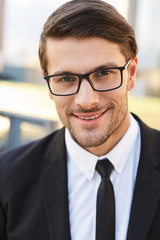 Handsome young businessman wearing suit walking outdoors