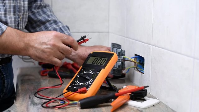 Electrician technician worker with the multimeter it measures the voltage in an electrical socket in a residential system. Construction industry. Building. Footage. 