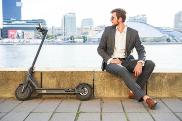 Young modern man using electric scooter on city street. Modern and ecological transportation concept. © opolja