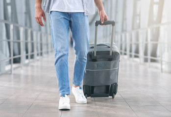Man walking with luggage at airport corridor