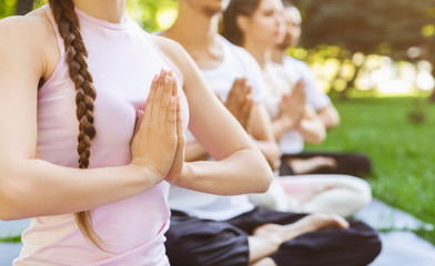 Close up of people making namaste gesture at yoga class outdoors - obrazy, fototapety, plakaty