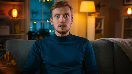 Portrait of a Handsome Man Sitting on a Couch at Home at Night, Watching Entertaining Movie on TV....