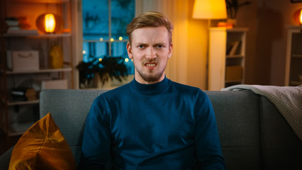 Portrait of a Handsome Man Sitting on a Couch at Home at Night, Watching Gore Horror Movie on TV....
