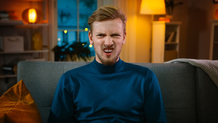 Portrait of a Handsome Man Sitting on a Couch at Home at Night, Watching Gore Horror Movie on TV....