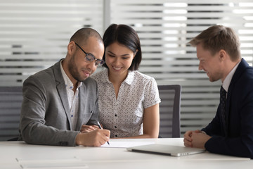 Happy mixed ethnicity young couple customers sign loan investment contract