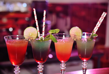 beautiful fresh alcoholic cocktails with mixed colored layers on the background of a bar in a nightclub.