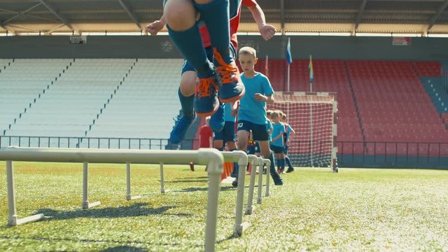 Panning shot of boys in soccer uniform exercising on empty stadium before training