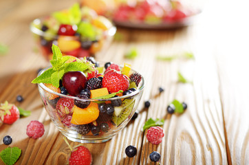 Assorted fruits in glass bowl on kitchen wooden table