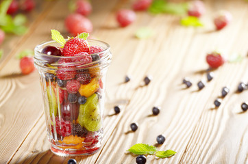 Assorted berries in mason jar on kitchen wooden table