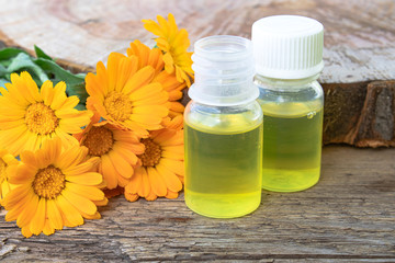 Bottle of calendula oil on a wooden background. Extract of tincture of calendula.