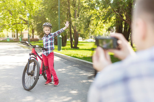 Dad is taking photo of his daughter with bike