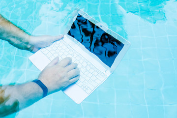 Male hands with a laptop working underwater. The concept of obstruction in the work. Blur Abstract...