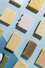 Flatlay of various natural hand-made soaps on blue, selective focus