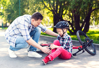 Father is comforting his girl after falling from bicycle