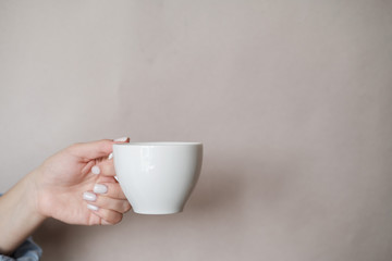 Woman holding cup of coffee. Female hands with cup of black tea on beige background. Close up
