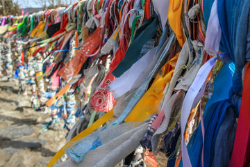 Multicolored ribbons tied to a holy place on Lake Baikal. Ribbons fluttering in the wind