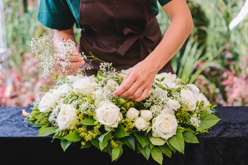 Gardener woman creating grave decoration