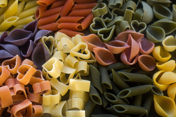 Various colorful raw pasta on rustic wooden table